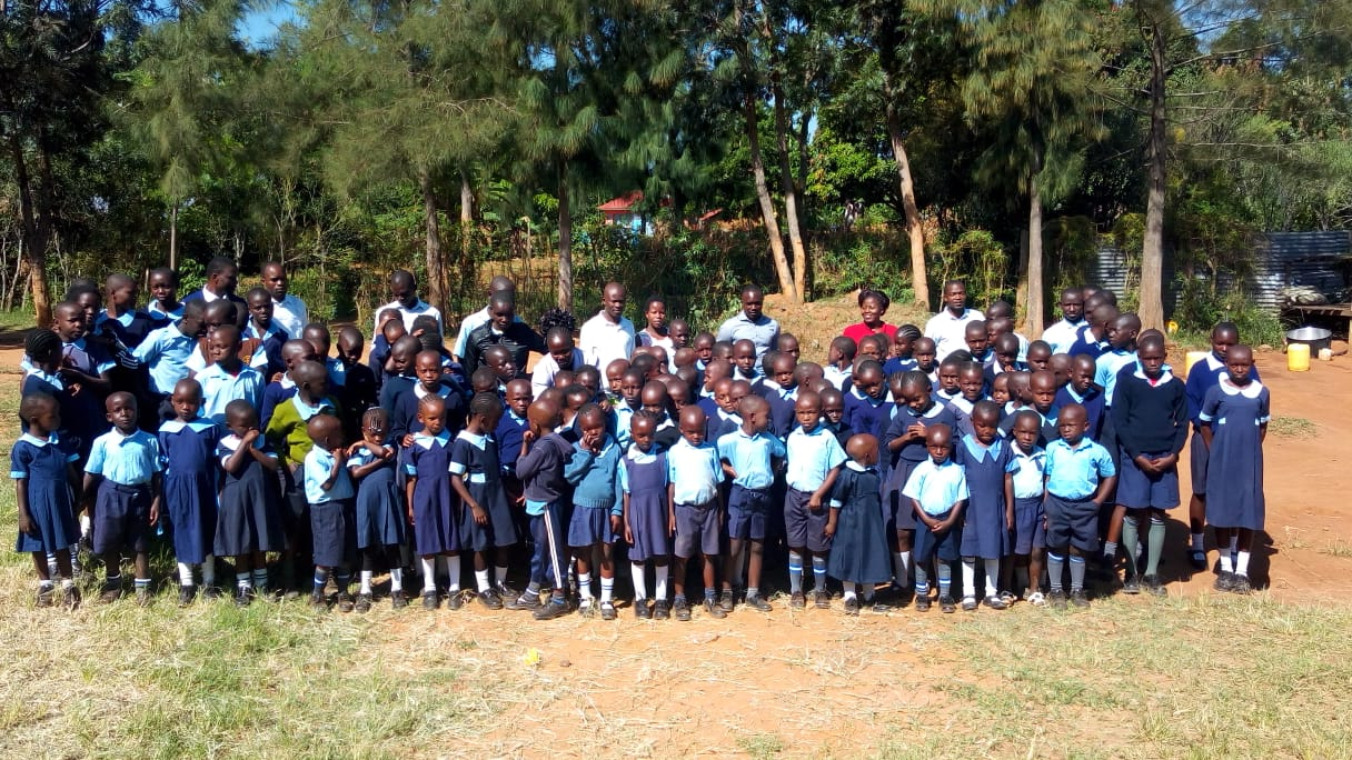 A large group of children are posing for a picture in a field.