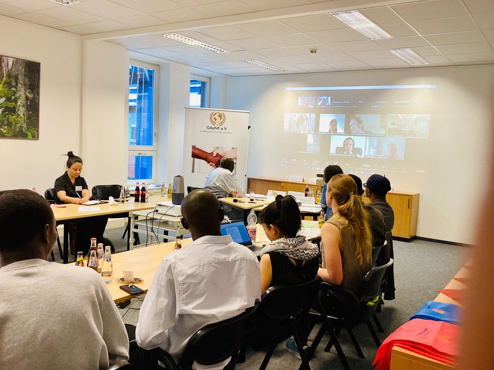 A group of people are sitting at tables in a room watching a presentation.