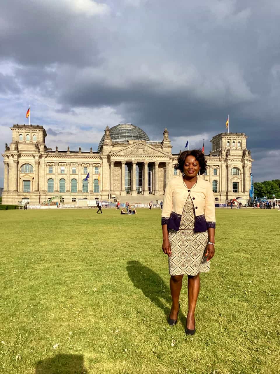 A woman in a dress is standing in front of a large building.