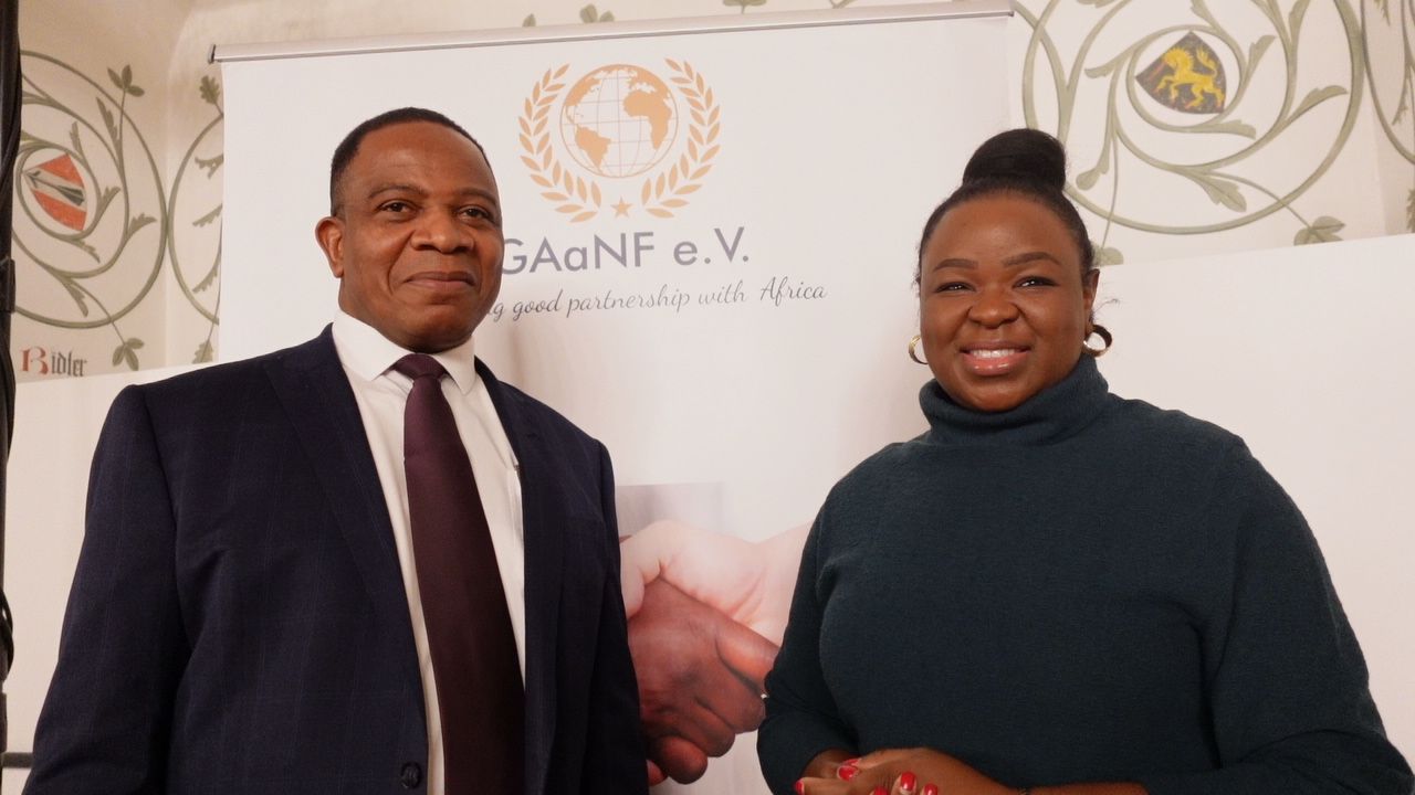 A man in a suit and tie is shaking hands with a woman in a turtleneck sweater.