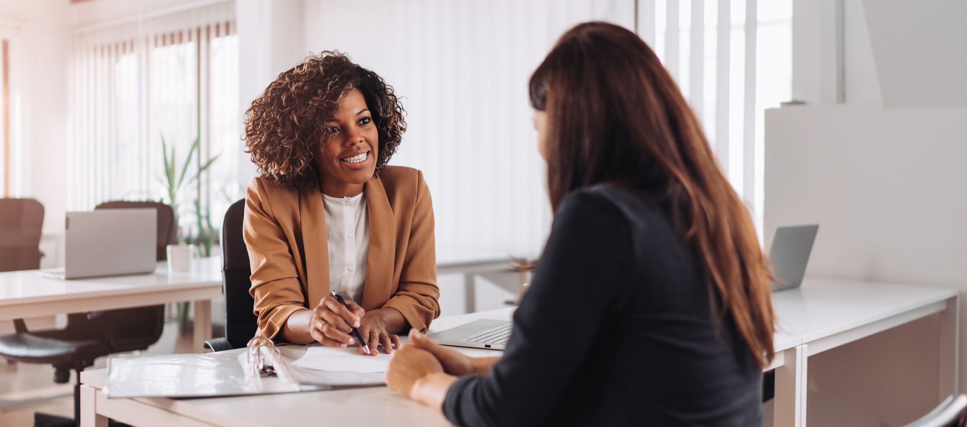 Two women are sitting at a table having a conversation.