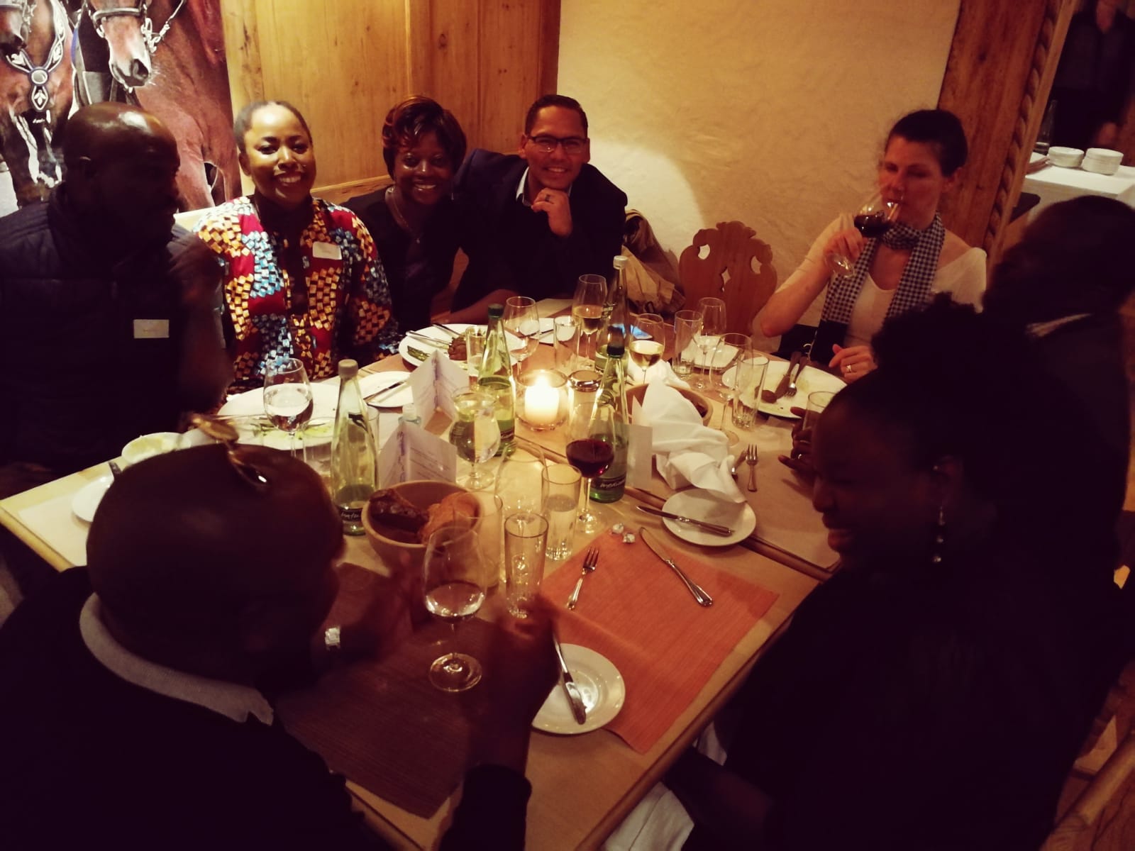 A group of people are sitting around a table with plates and glasses