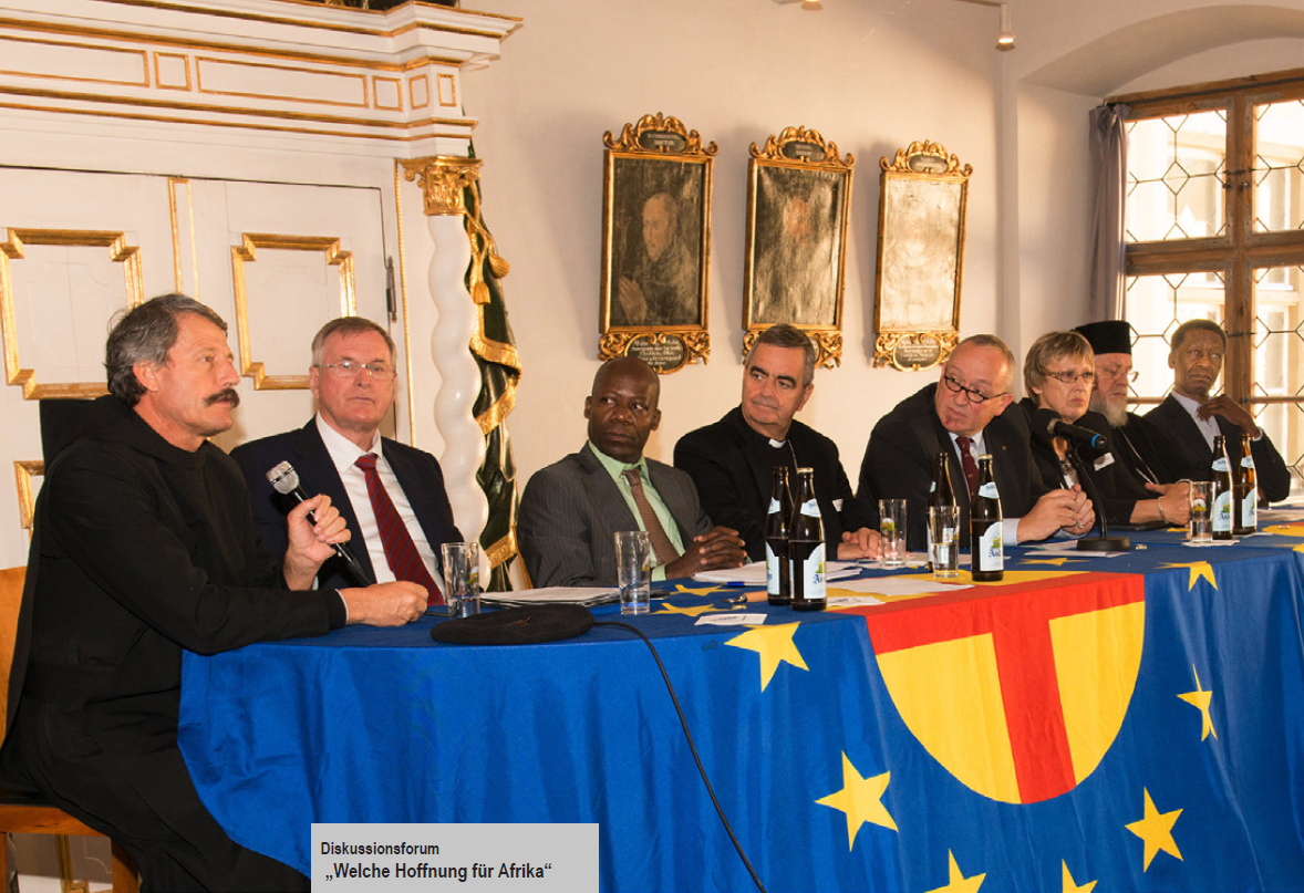 A group of men are sitting at a table with a flag on it