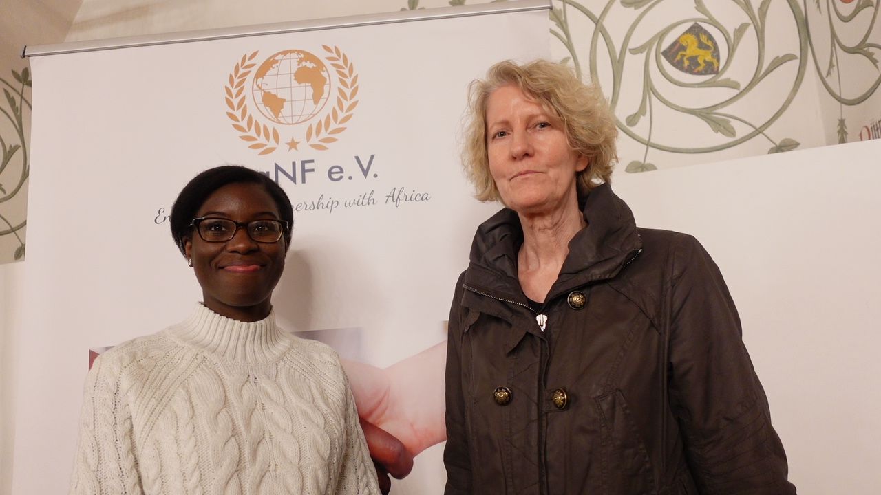 Two women are standing next to each other in front of a sign that says nf e.v.