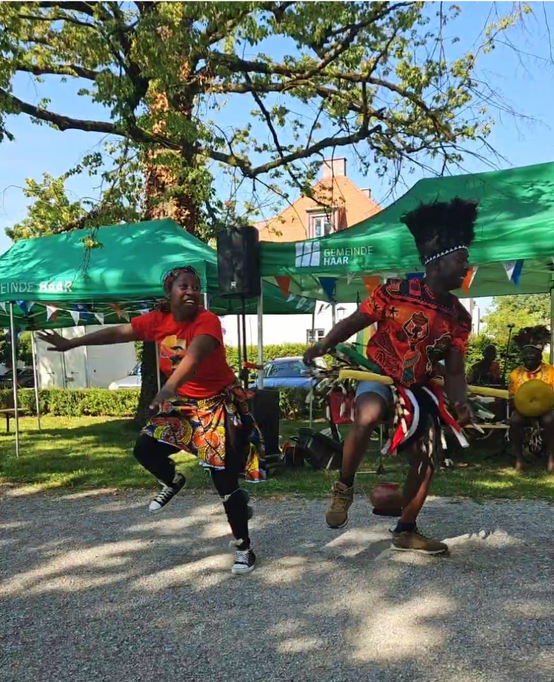Two people are dancing in front of a green tent that says coca cola