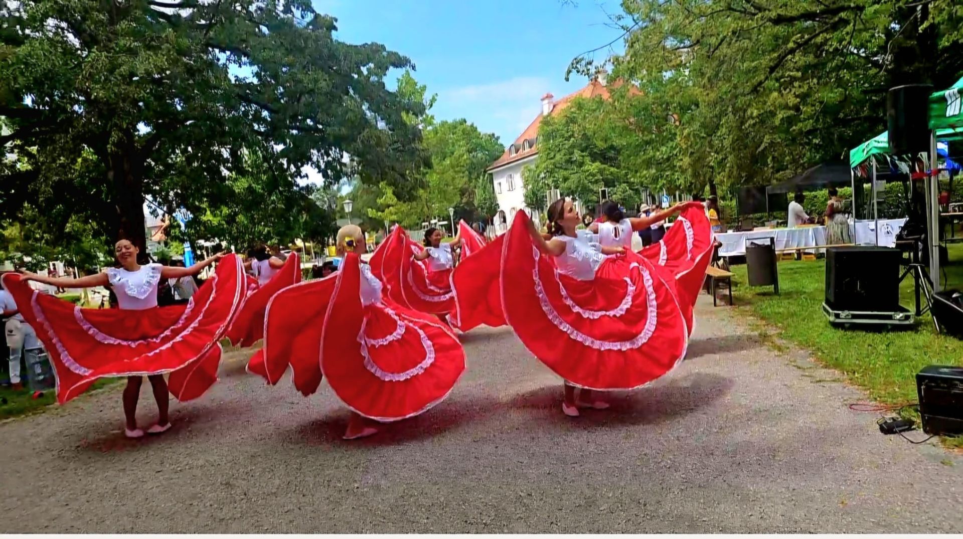 Eine Gruppe von Frauen in roten Kleidern tanzt in einem Park