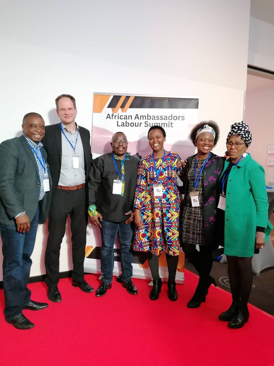 A group of people are posing for a picture on a red carpet.