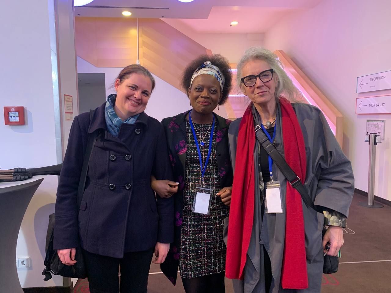 Three women are posing for a picture in a hallway.