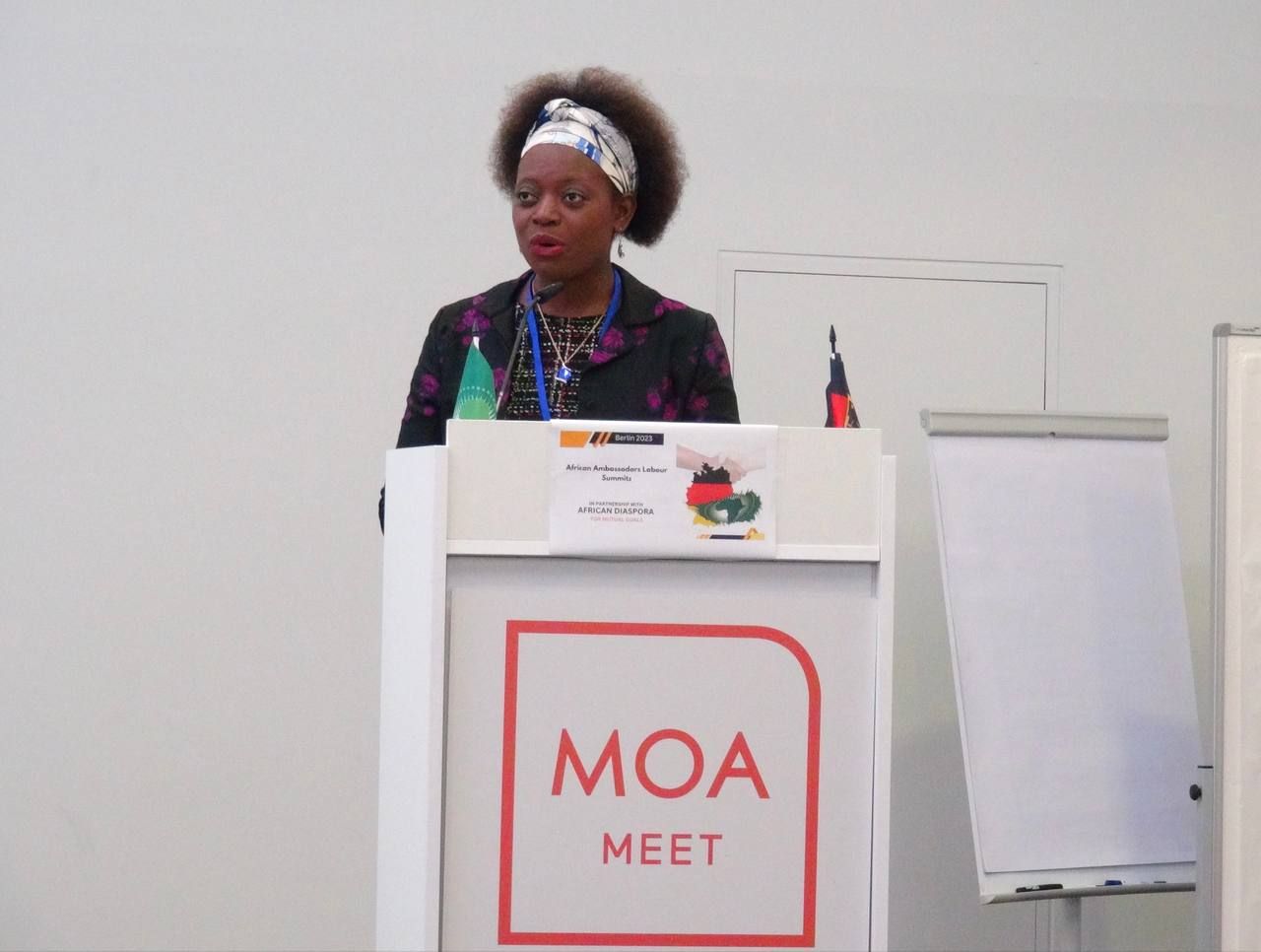 A woman stands at a podium that says moa meet