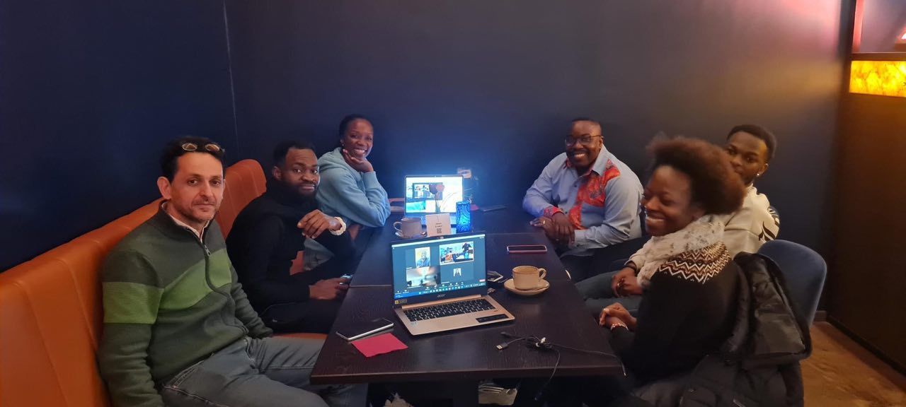 A group of people are sitting around a table with laptops.