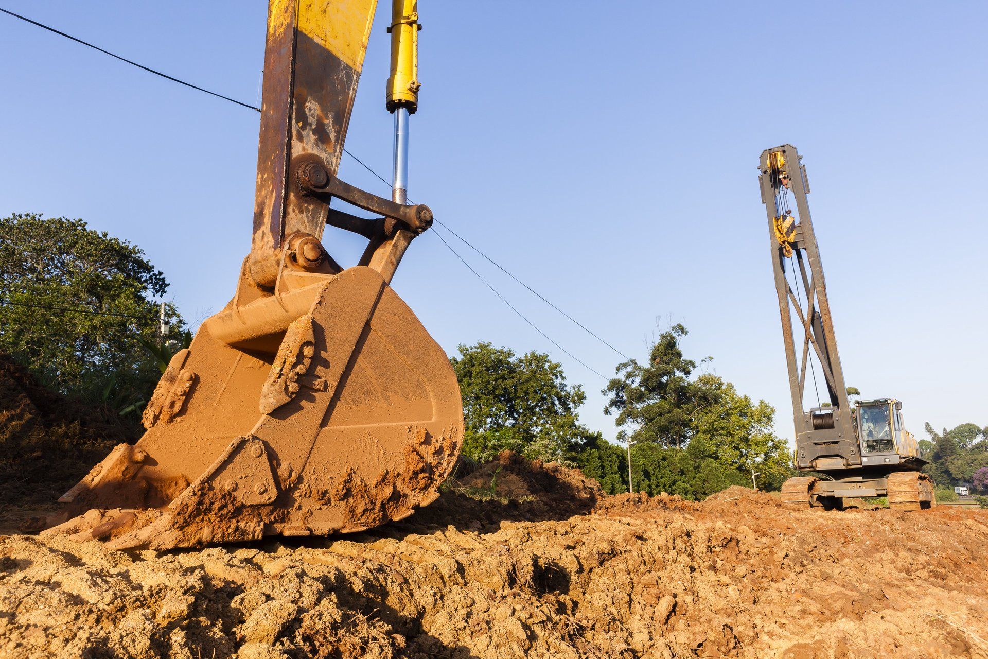 A yellow excavator is digging a hole in the dirt at a construction site.