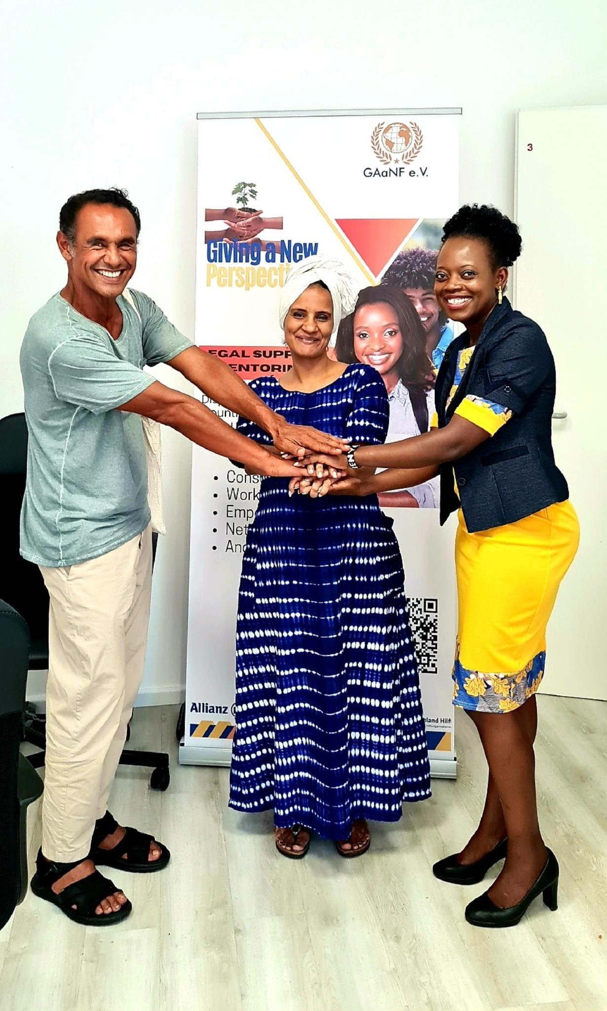 A man and two women are holding hands in front of a banner.