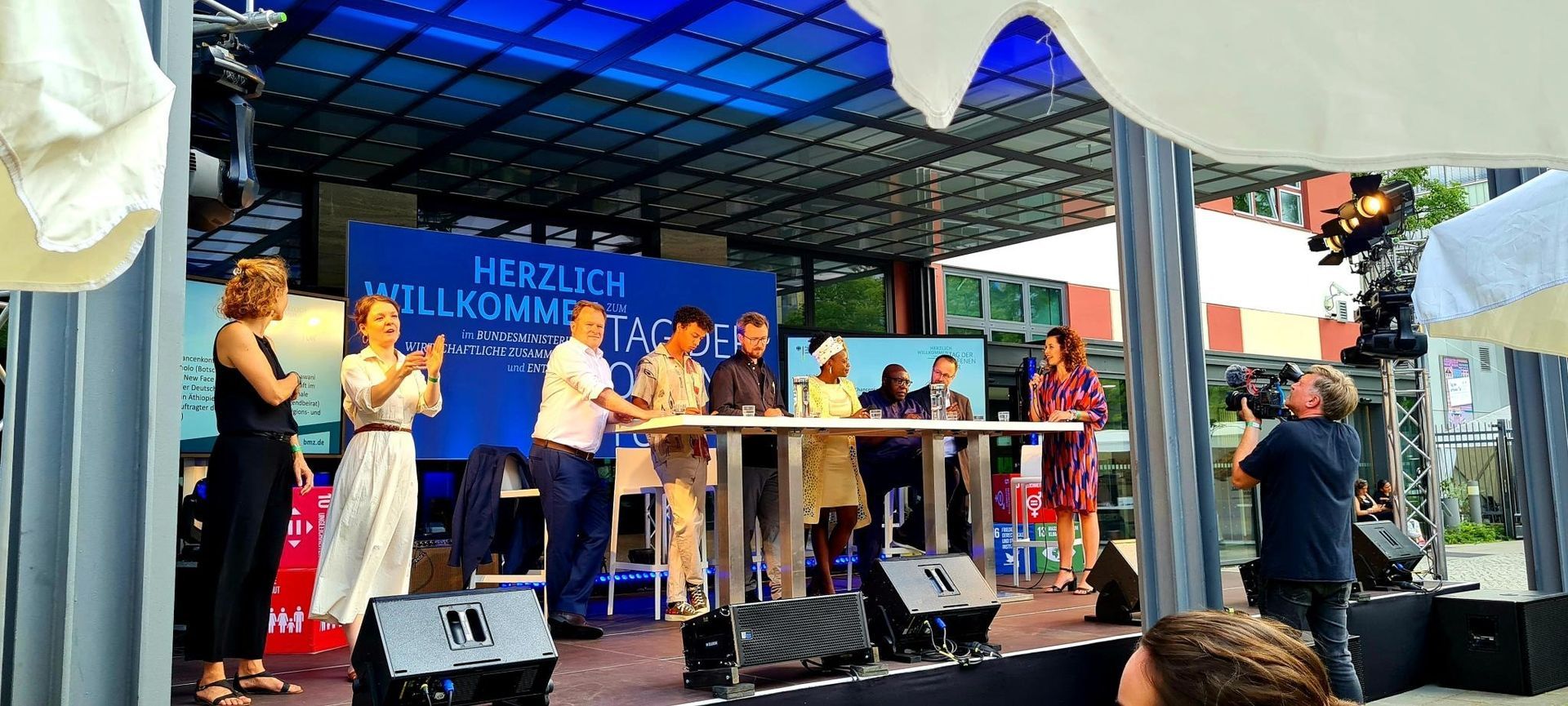 A group of people are standing on a stage talking to each other.