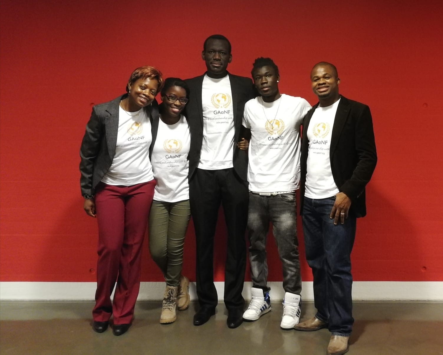 A group of people standing in front of a red wall