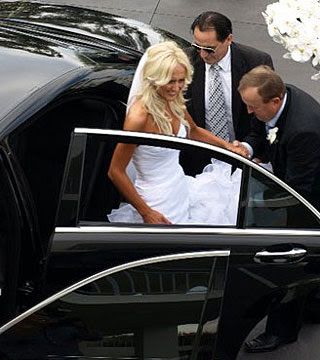 A bride and groom are getting out of a black car