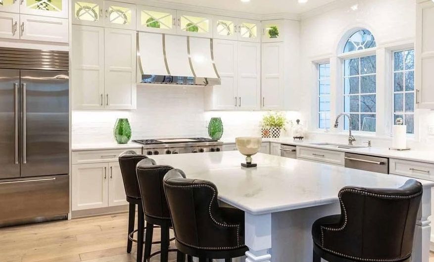 A kitchen with white cabinets and stainless steel appliances and a large island.