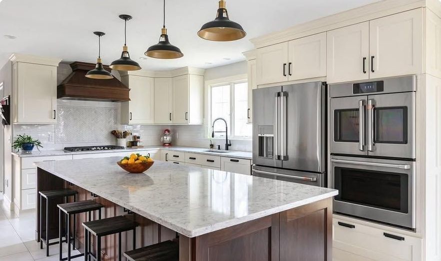 A kitchen with white cabinets , stainless steel appliances and a large island.