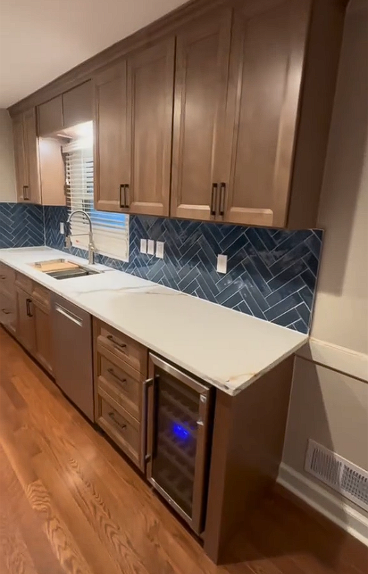 A kitchen with wooden cabinets , stainless steel appliances , and a wine cooler.