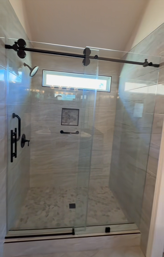 A bathroom with a sliding glass shower door and a shower head.