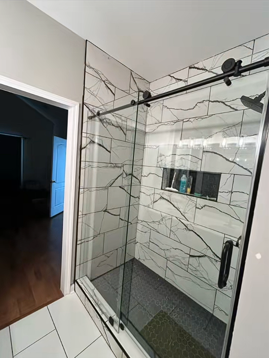 A bathroom with a sliding glass shower door and white tiles.