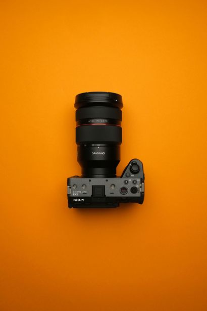 橙色背景上擺放著一台帶有大鏡頭的黑色相機。