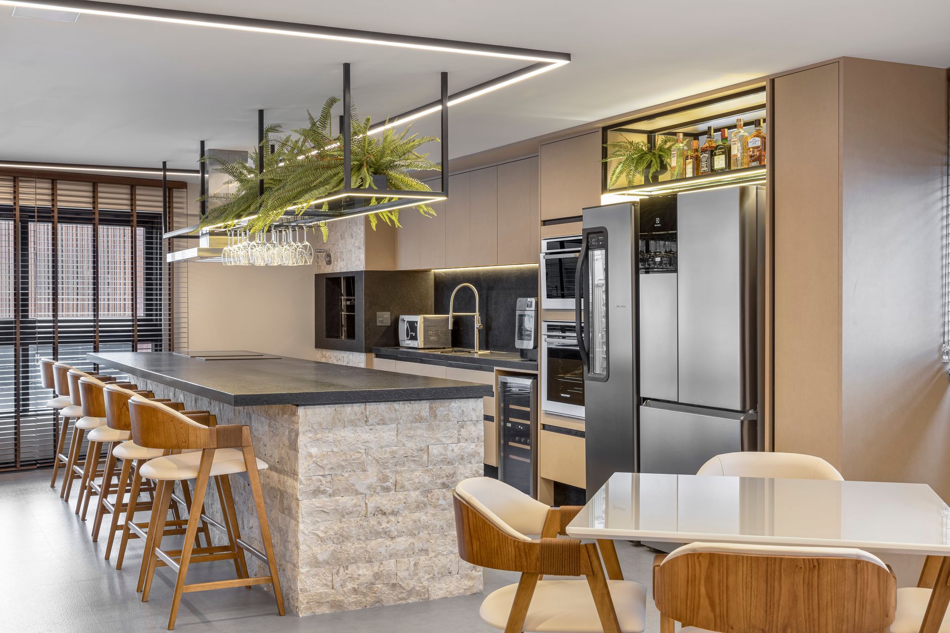 Cozinha moderna com ilha, bancadas de granito e eletrodomésticos de aço inoxidável; inclui área verde e área de jantar.