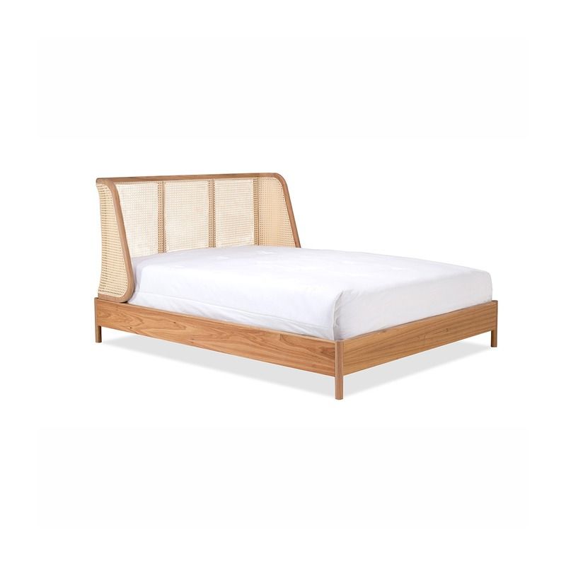 Cama de madeira com cabeceira de vime, lençóis brancos.