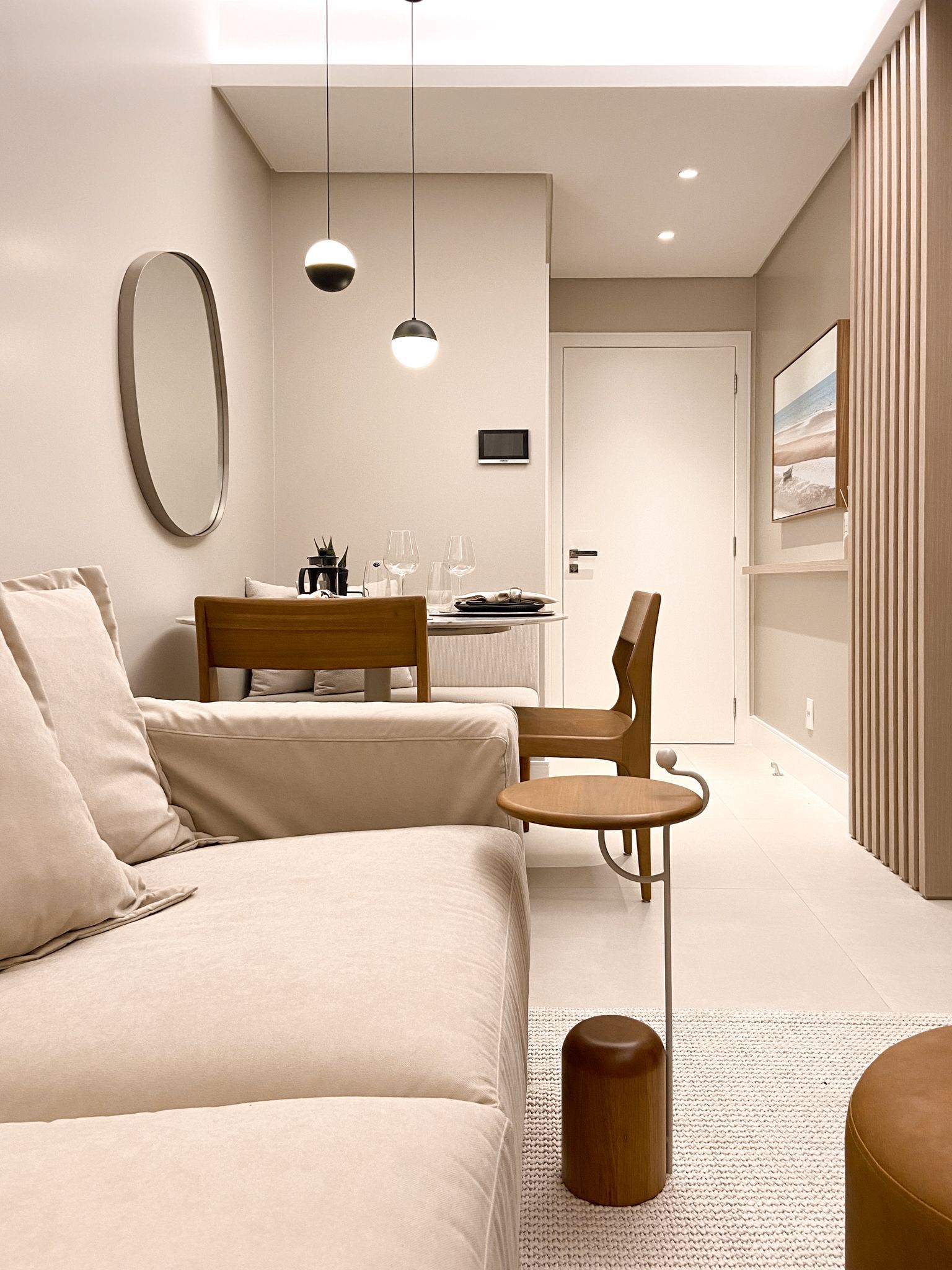 Sala de estar com sofá bege, móveis de madeira e paredes brancas.