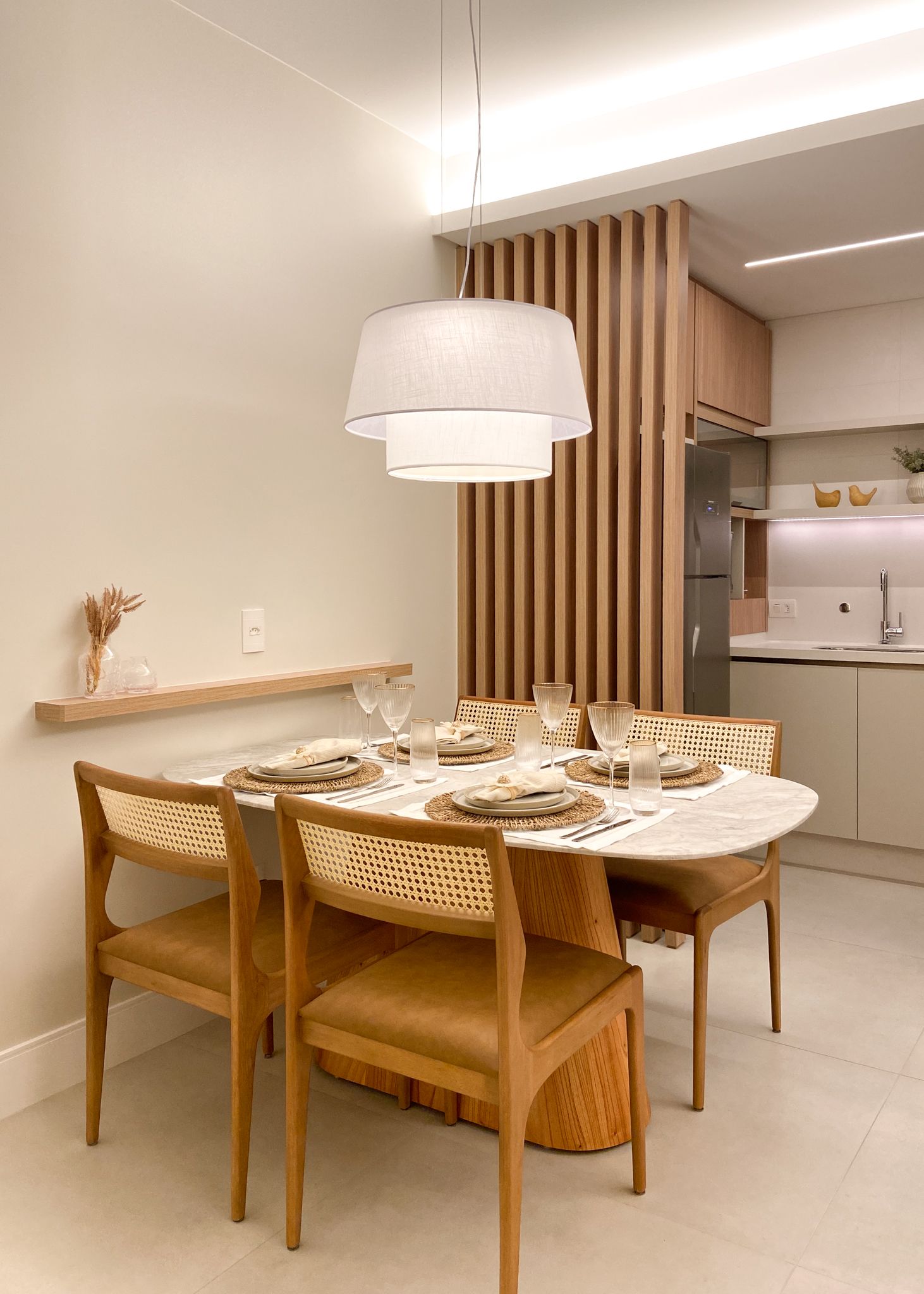 Sala de jantar com mesa de madeira, cadeiras e luminária pendente; paredes bege claro.
