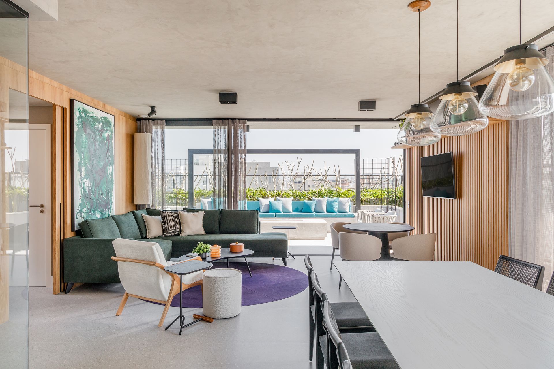 Sala de estar moderna com sofá verde, mesa de jantar e acesso ao terraço externo.
