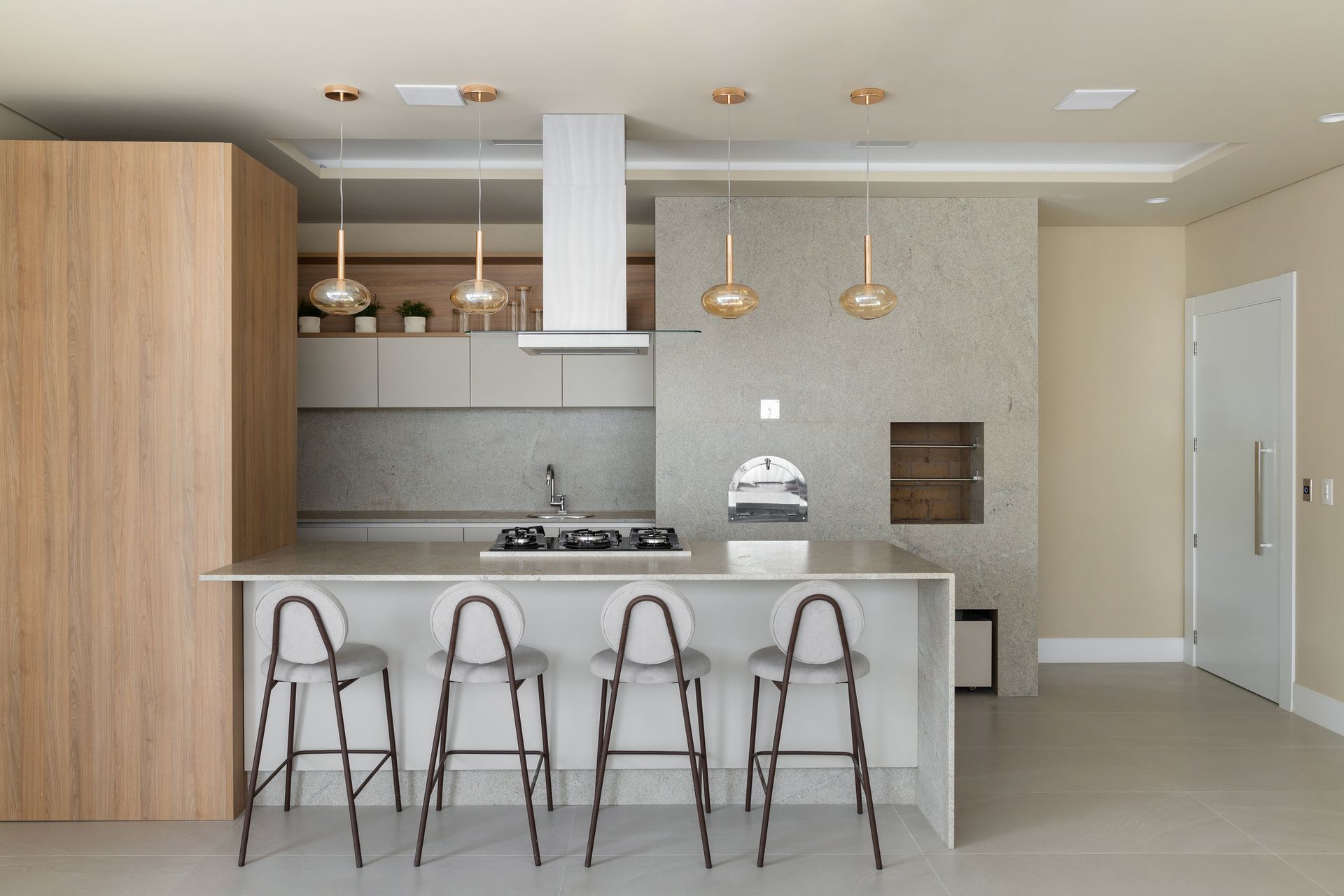 Cozinha moderna com paleta de cores claras, bancos de bar e iluminação suspensa.