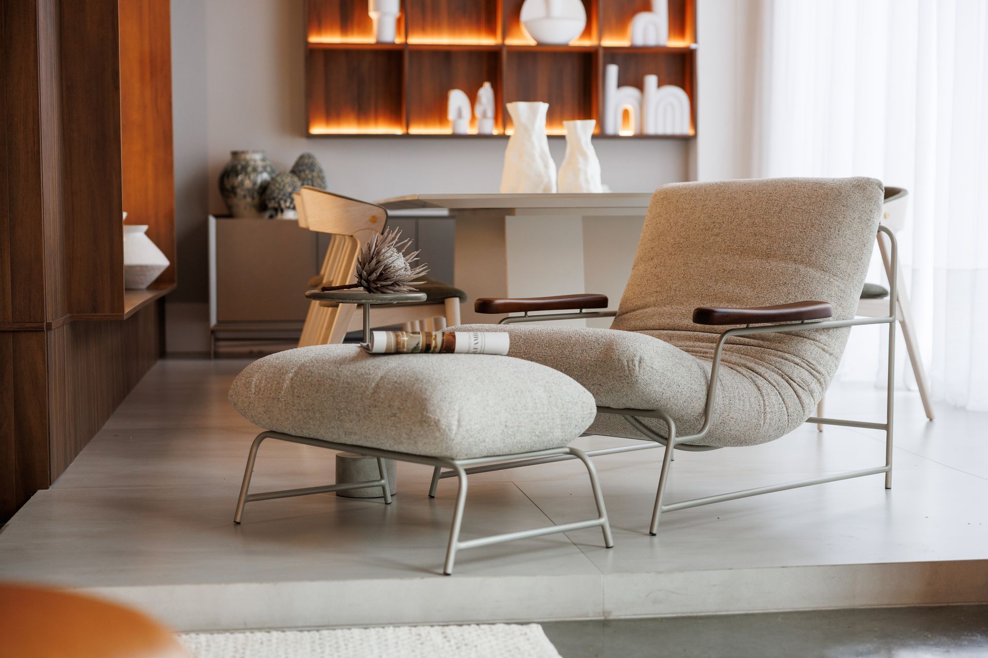 Poltrona e pufe aconchegantes em um quarto moderno, cores neutras, mesa pequena com decoração.