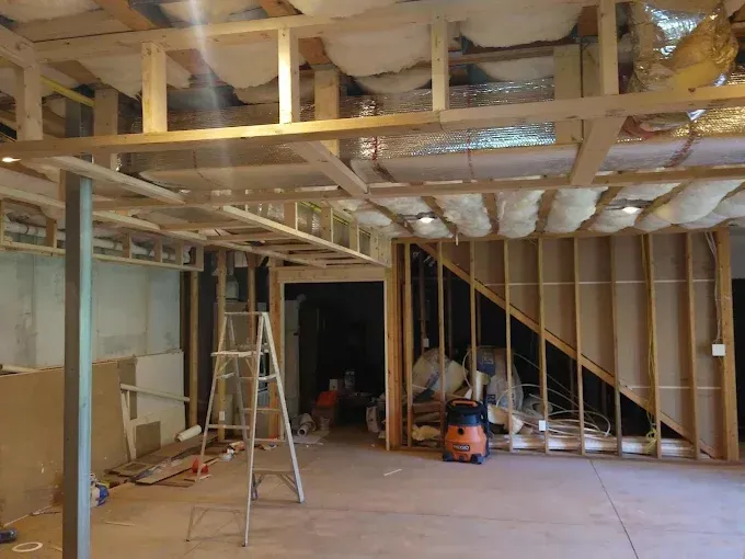 A room with a ladder and a vacuum cleaner in it.