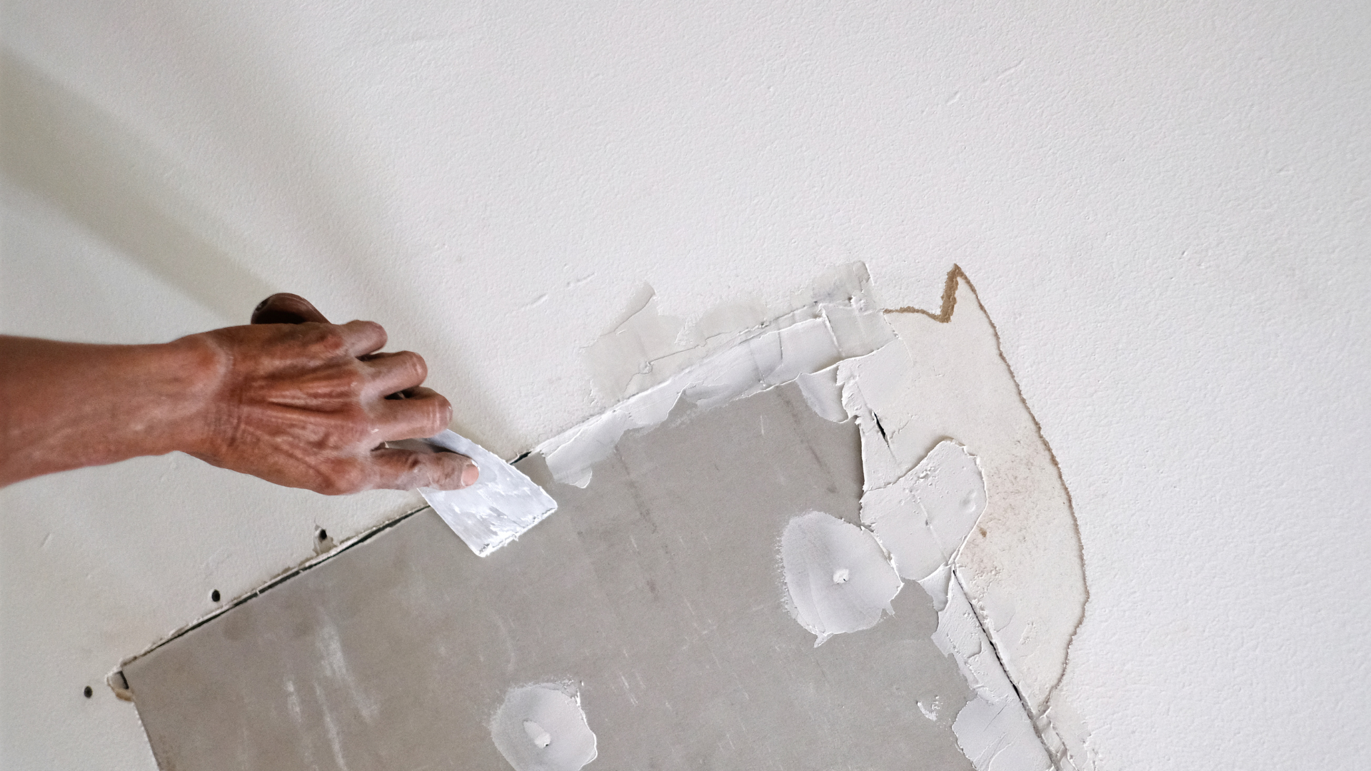 A person is plastering a wall with a spatula.