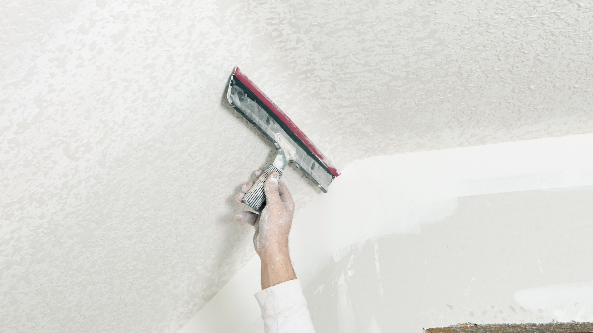 A person is cleaning a ceiling with a squeegee.