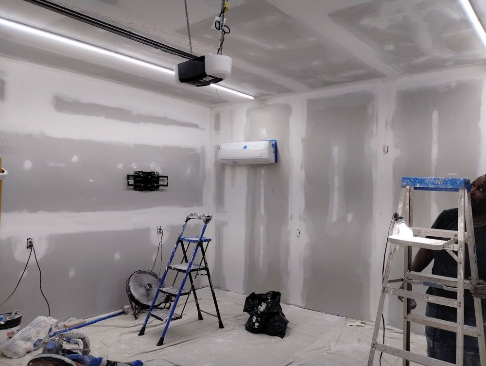 A man is standing on a ladder in a room that is being remodeled.