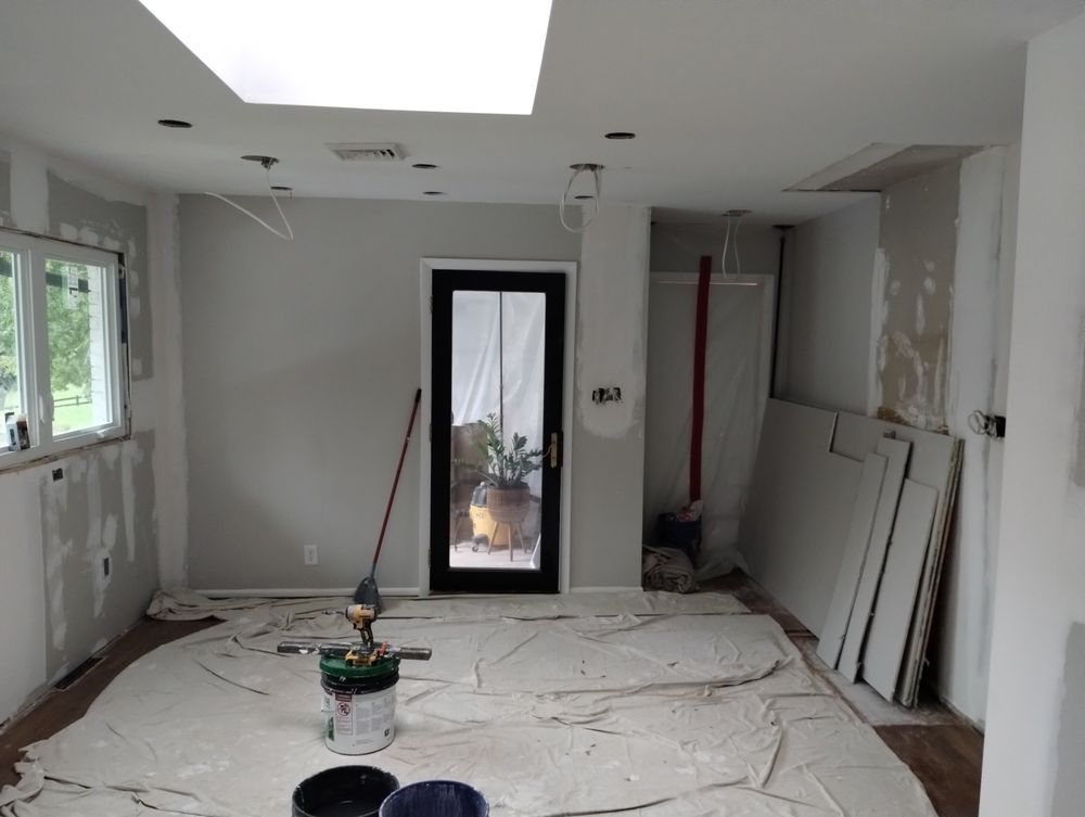 A room is being painted with buckets of paint and a mop.