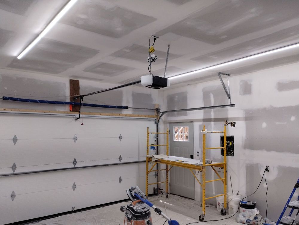 A garage with a garage door open and a vacuum cleaner hanging from the ceiling.