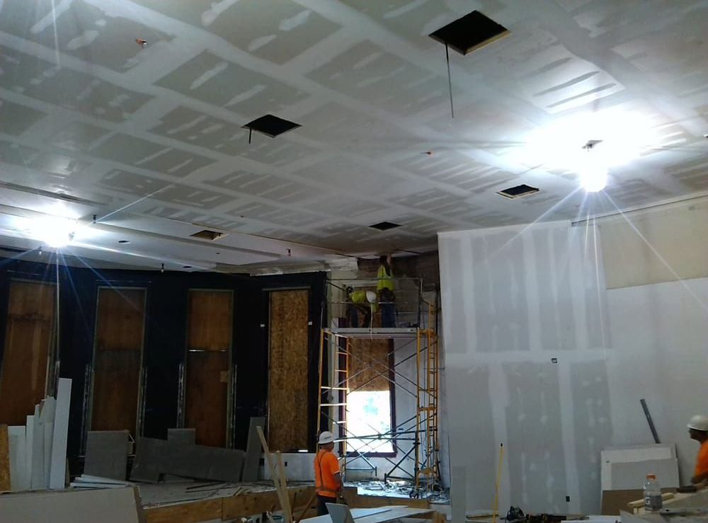 A man is standing on a scaffolding in a room under construction