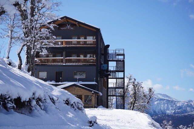 Un gran edificio está situado en la cima de una colina cubierta de nieve.
