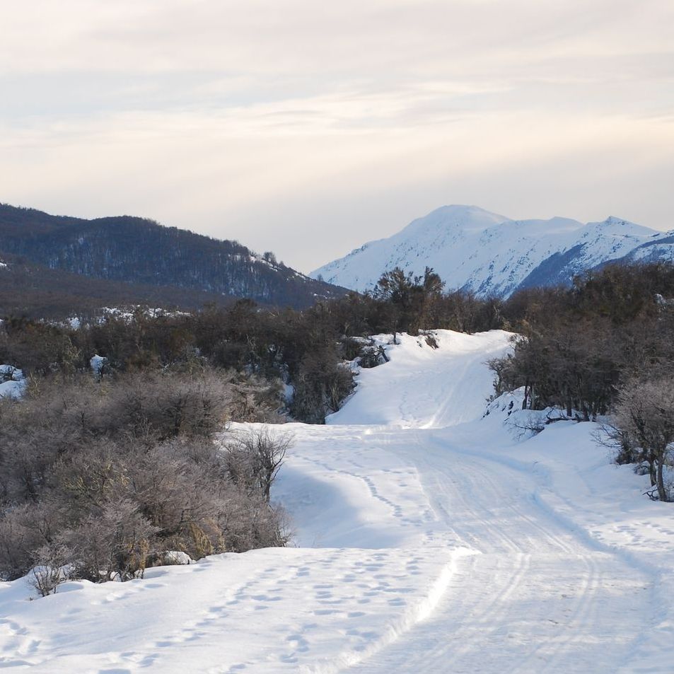 Una carretera nevada con montañas al fondo