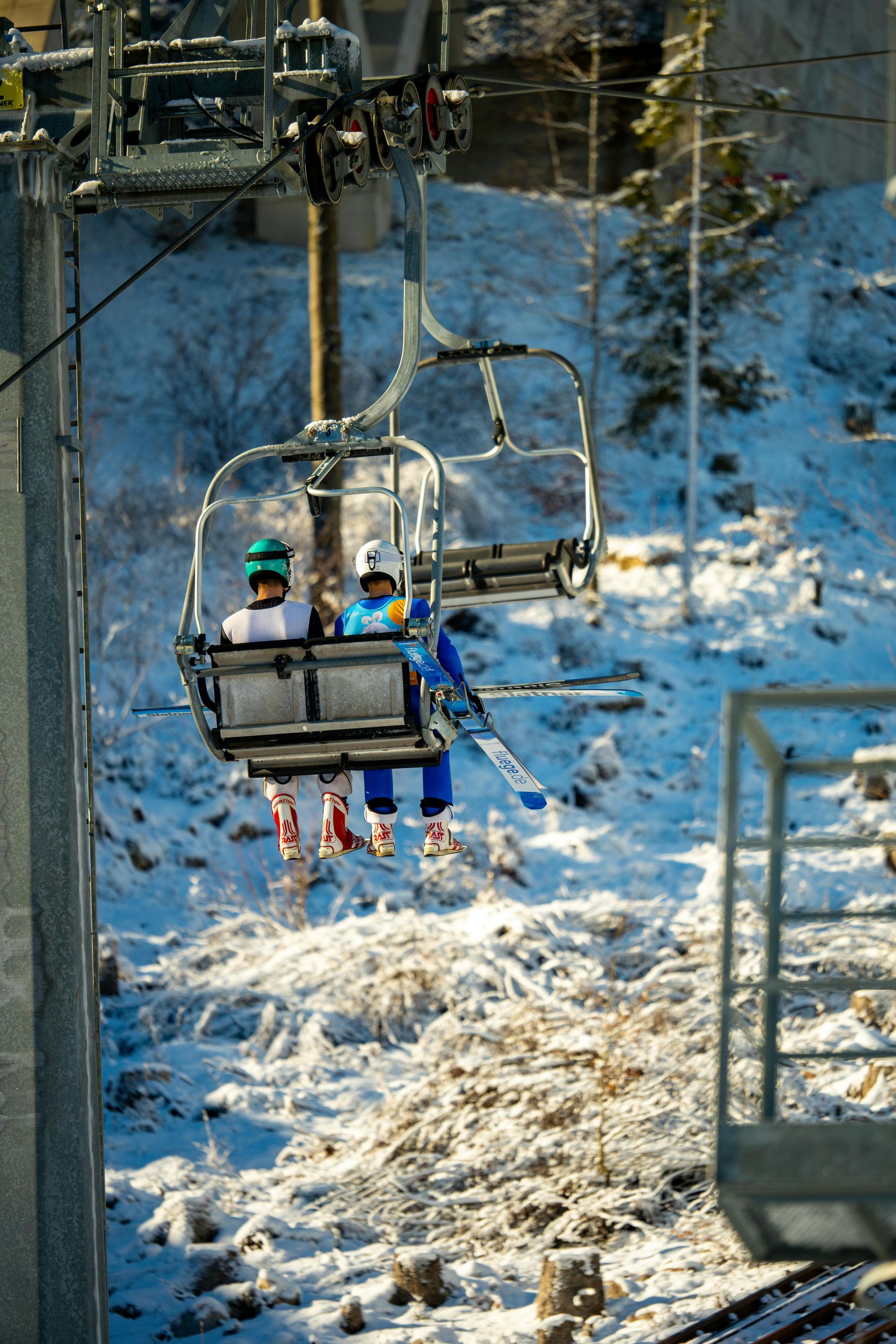 Dos personas viajan en un telesquí en la nieve.