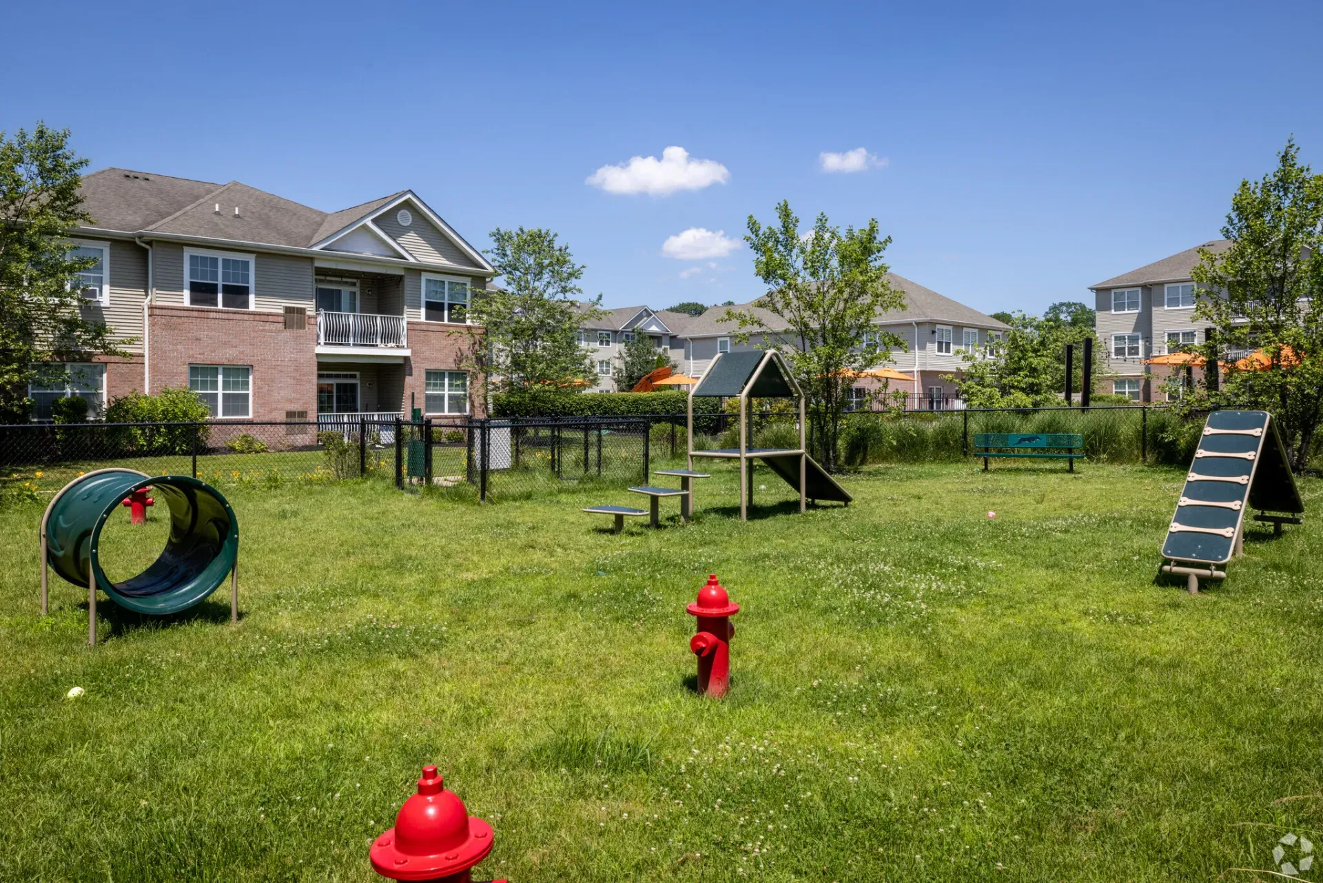 Playground in an apartment community with a slide, climbing structure, and grassy field.