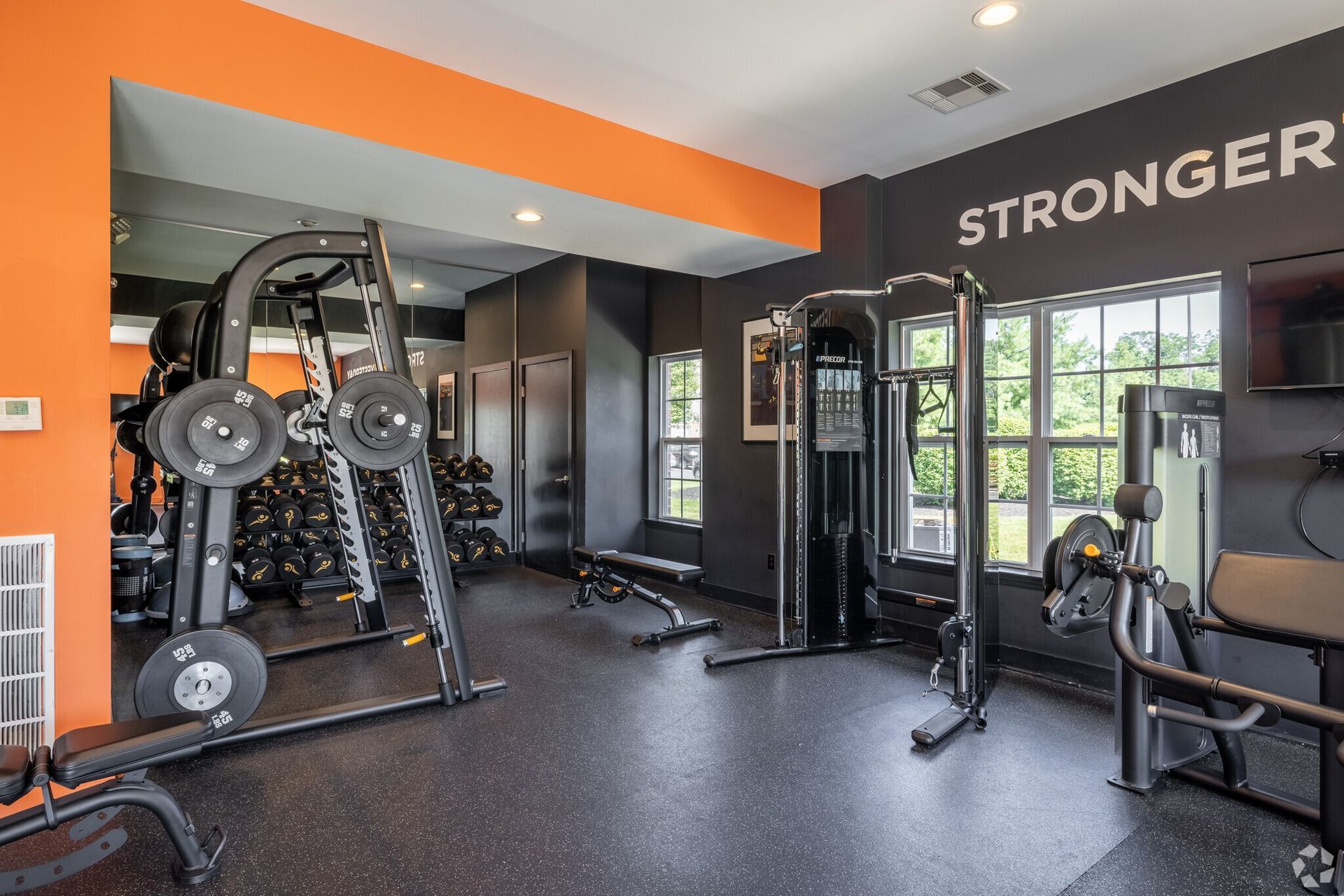 Well-lit indoor fitness center with weight machines, benches, and free weights.