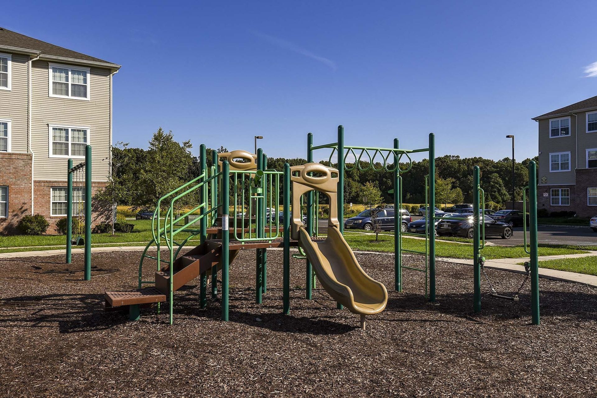 Playground with slides and climbing structure in a residential community courtyard.