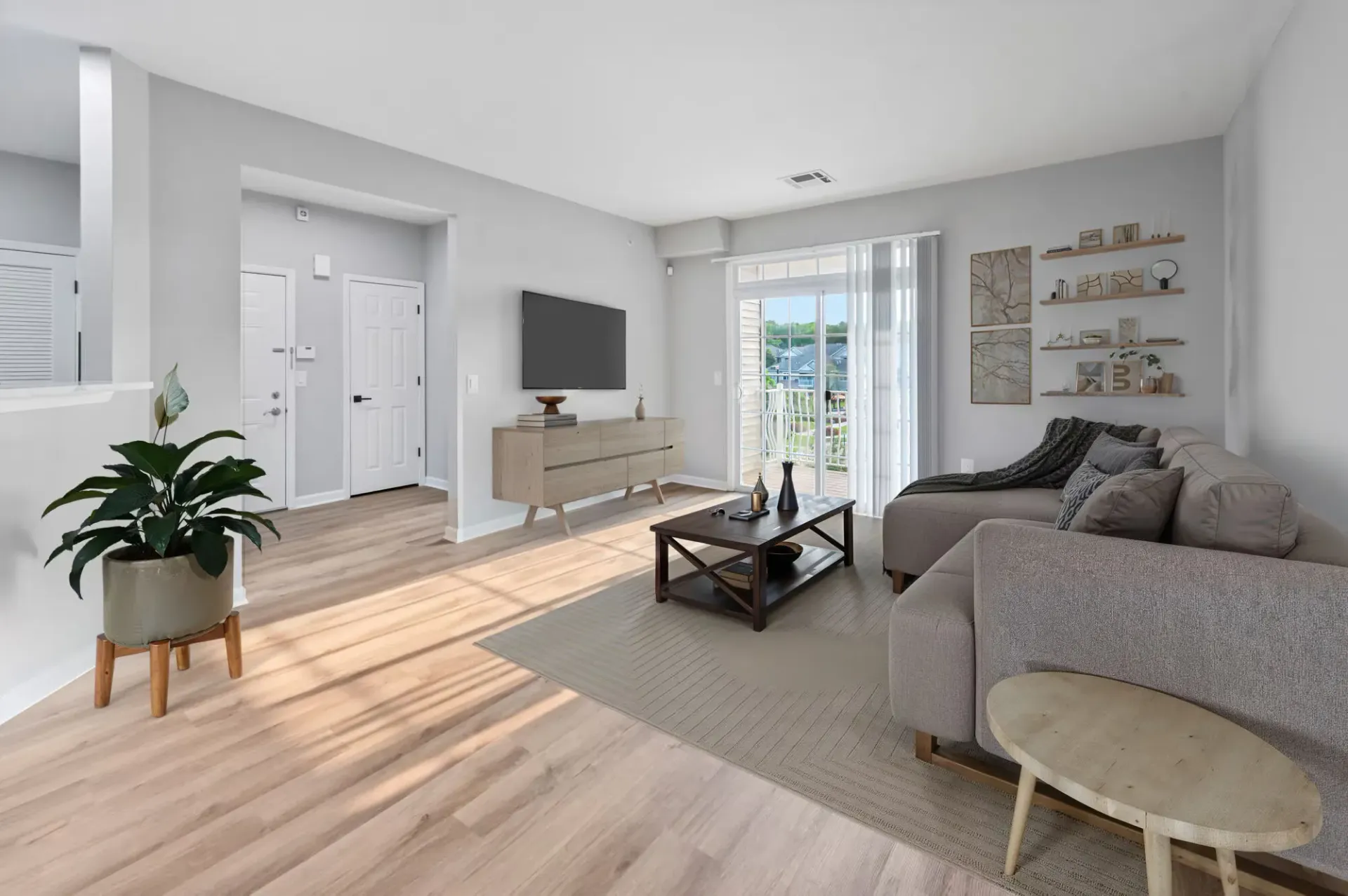 Bright living room in a modern apartment with a sofa, TV, and glass balcony doors.