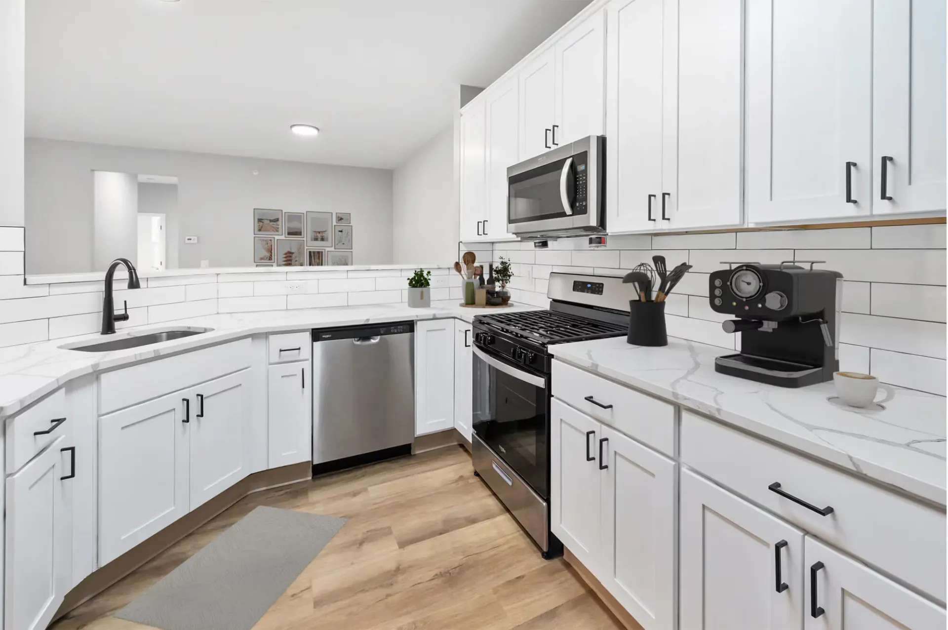 Modern white kitchen with stainless-steel appliances and marble countertops.