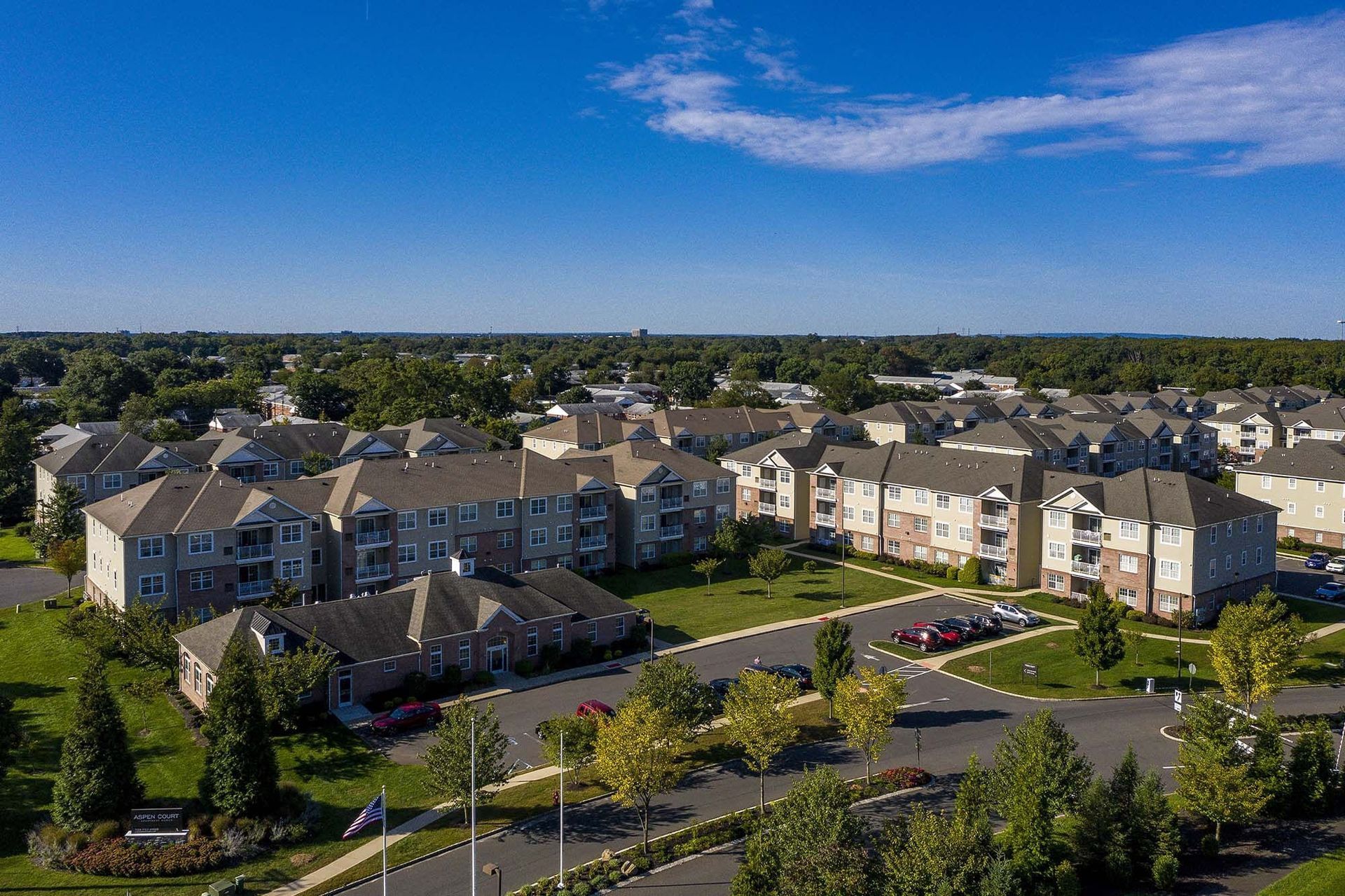 Aerial view of a large apartment community with multiple buildings, green lawns, and parking lots.