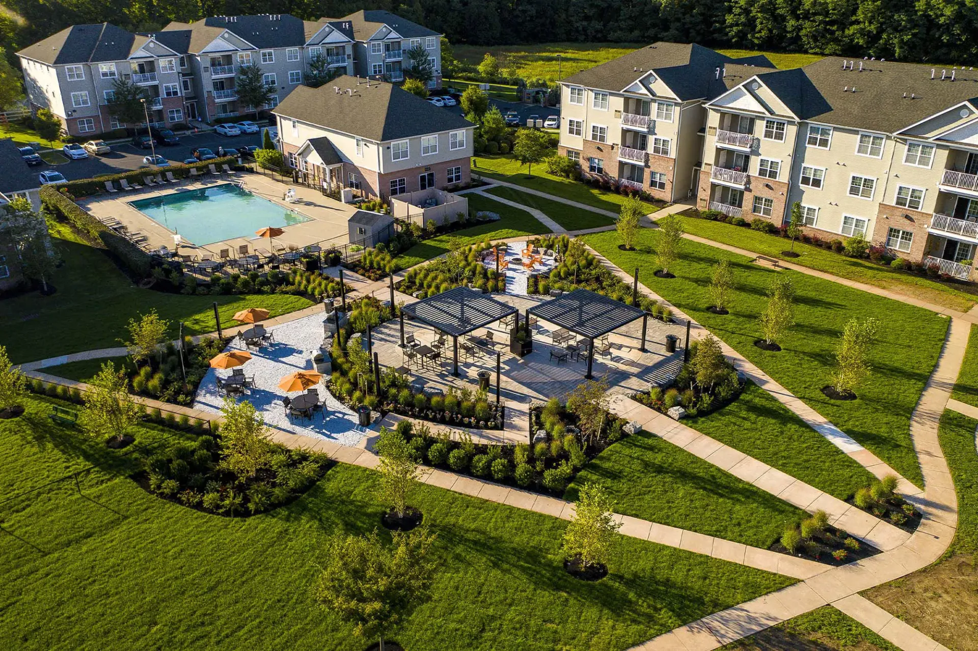 Aerial view of a residential apartment community with a pool, clubhouse, and landscaped courtyards.