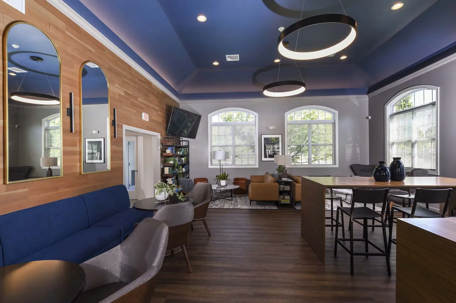 Interior community lounge with blue ceiling, wood accent wall, and assorted seating.